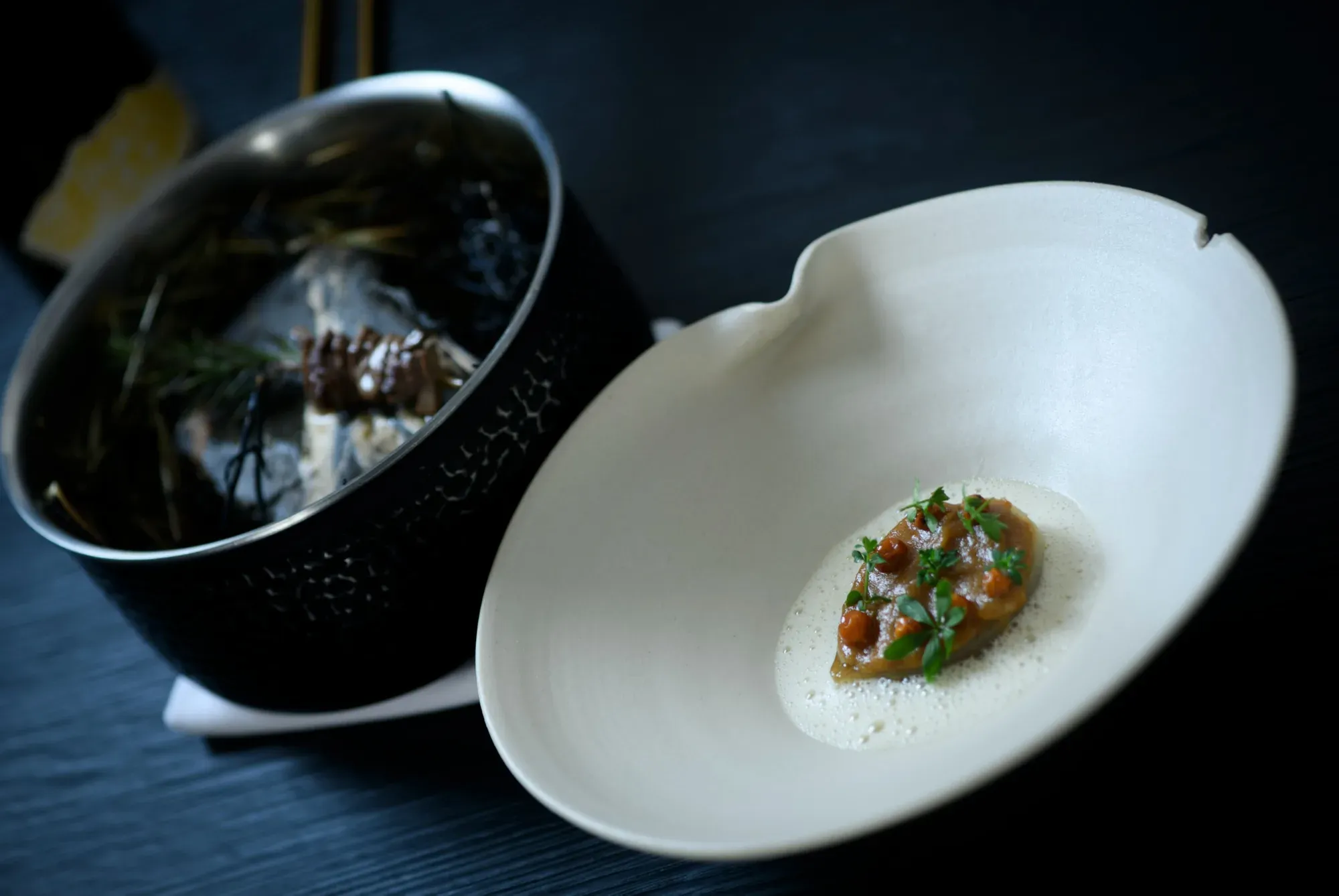 A tartare in a white bowl, served with a dark ceramic pot, at the Chef's Table by Gesser