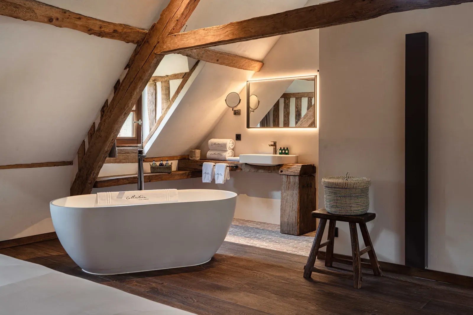A freestanding bathtub under the roof beams of La Grande Forge