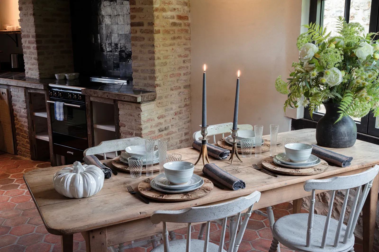 A dinner table laid with candles and flowers in the kitchen of La Grande Forge