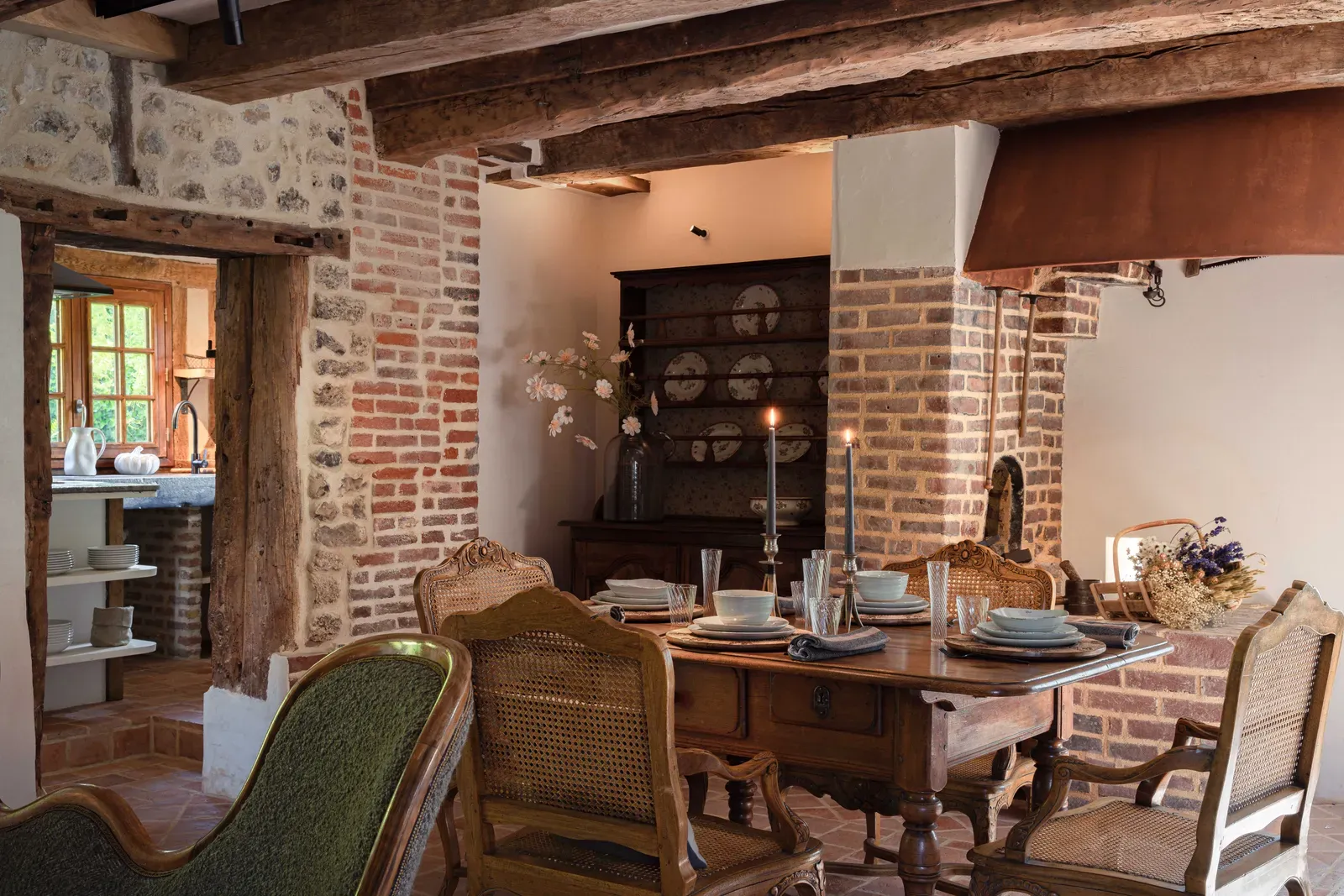 The dining room of La Petite Forge with antique chairs and a brick fireplace