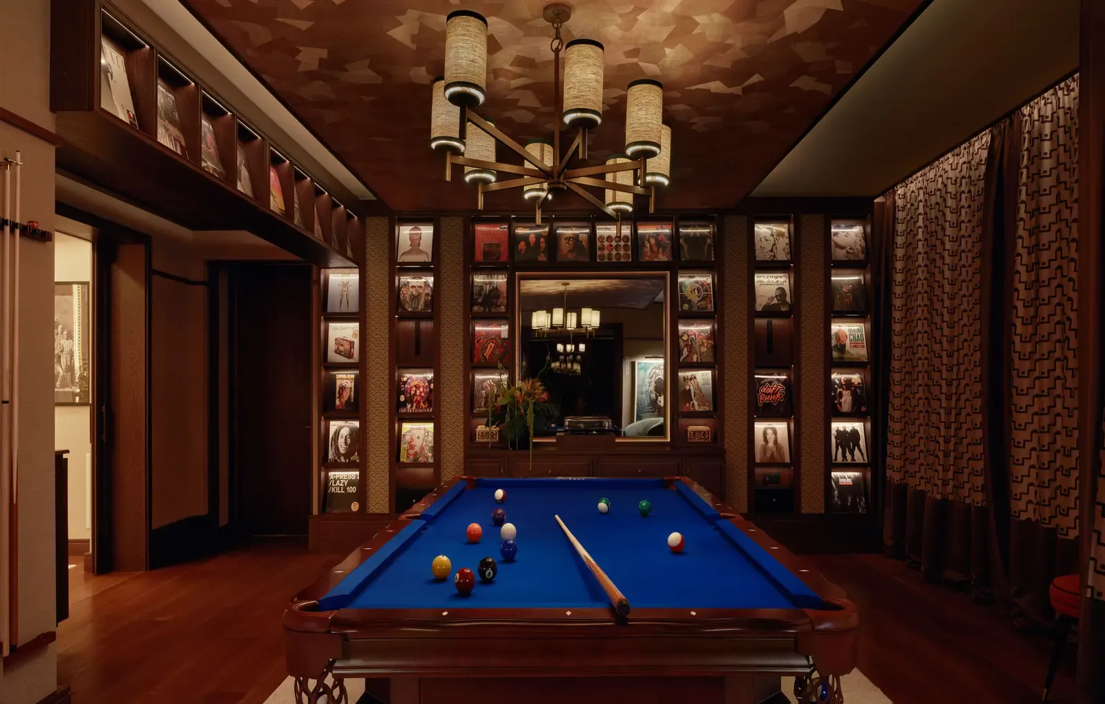 The games room of the COYA Suite with a billiard table under a chandelier