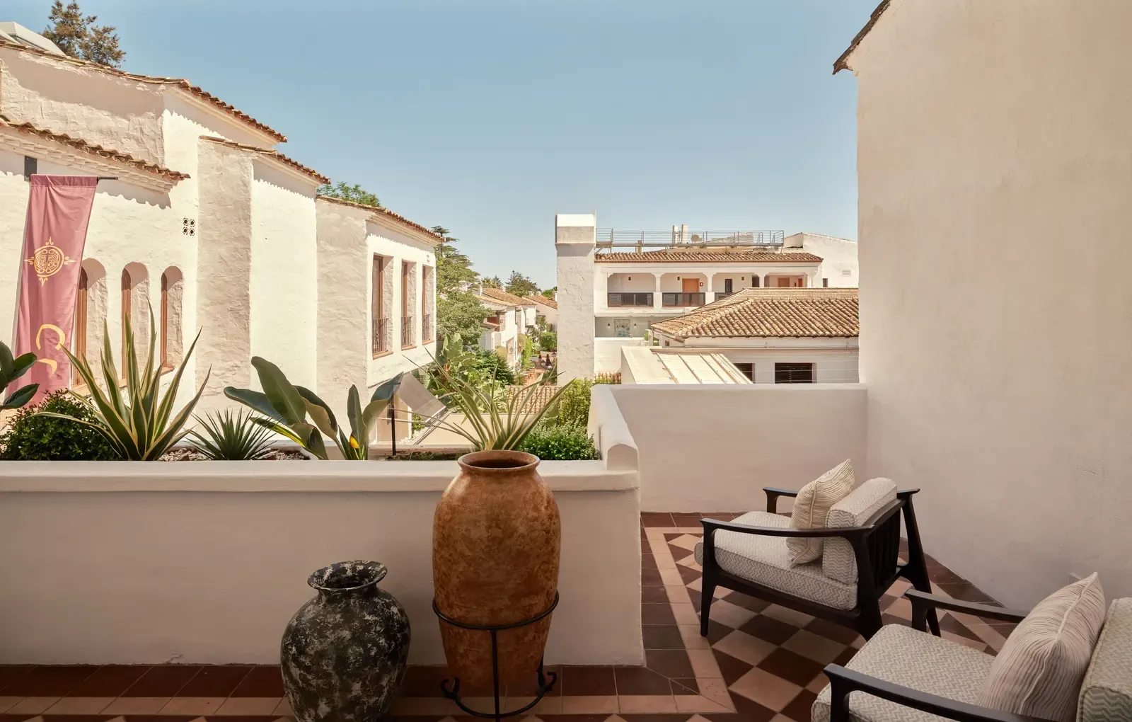 The terrace of the COYA Suite Marbella with lounge chairs, plants and whitewashed Andalusian houses