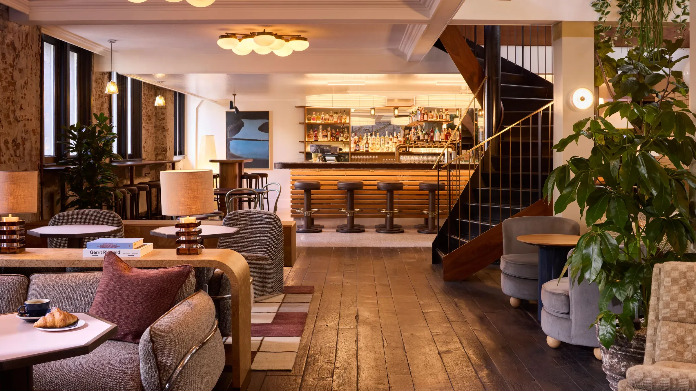 The redesigned lobby of The Hoxton, Amsterdam with sofas, plants and Lotti's Bar in the background