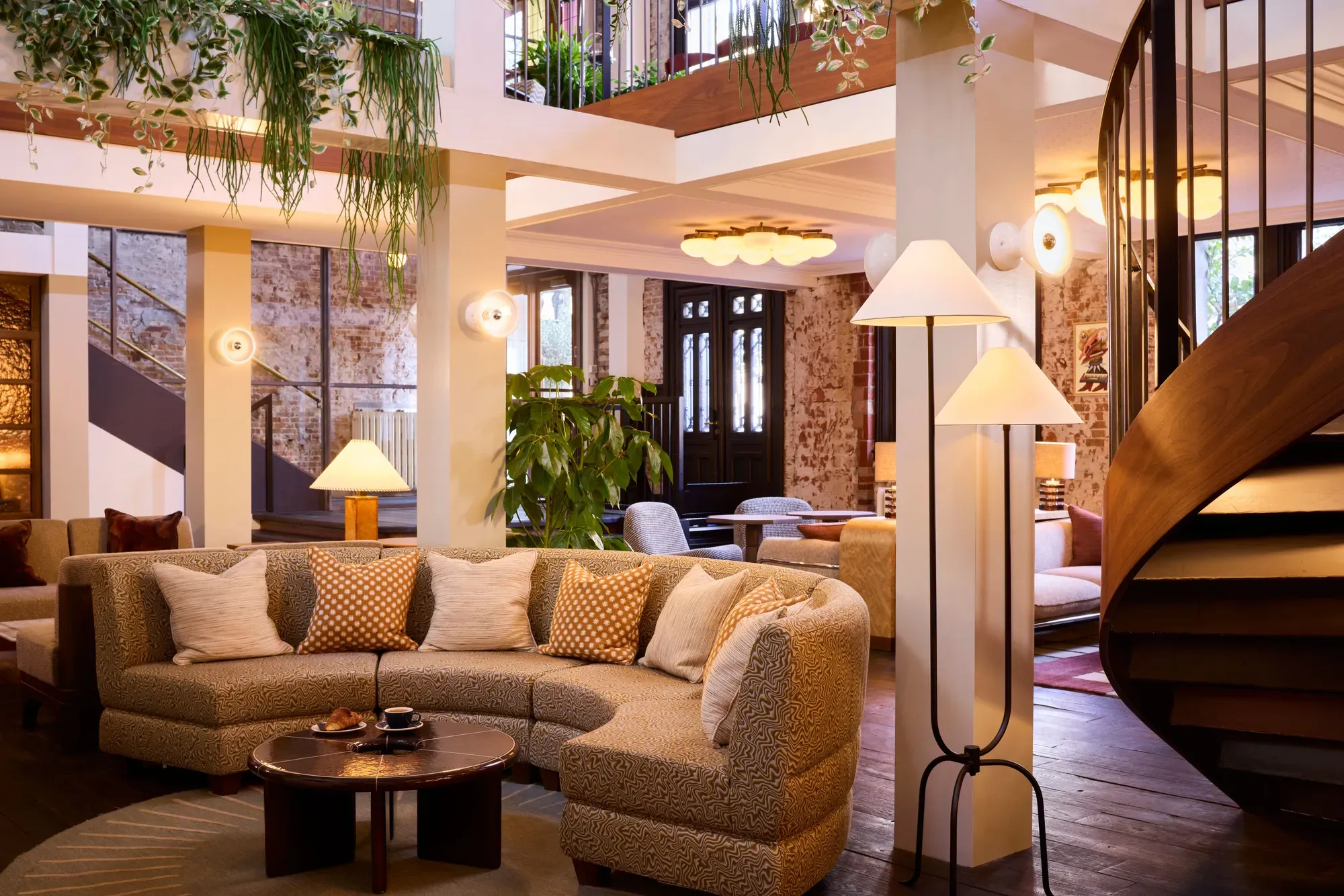 The redesigned lobby lounge of The Hoxton, Amsterdam with curved sofas and a spiral staircase