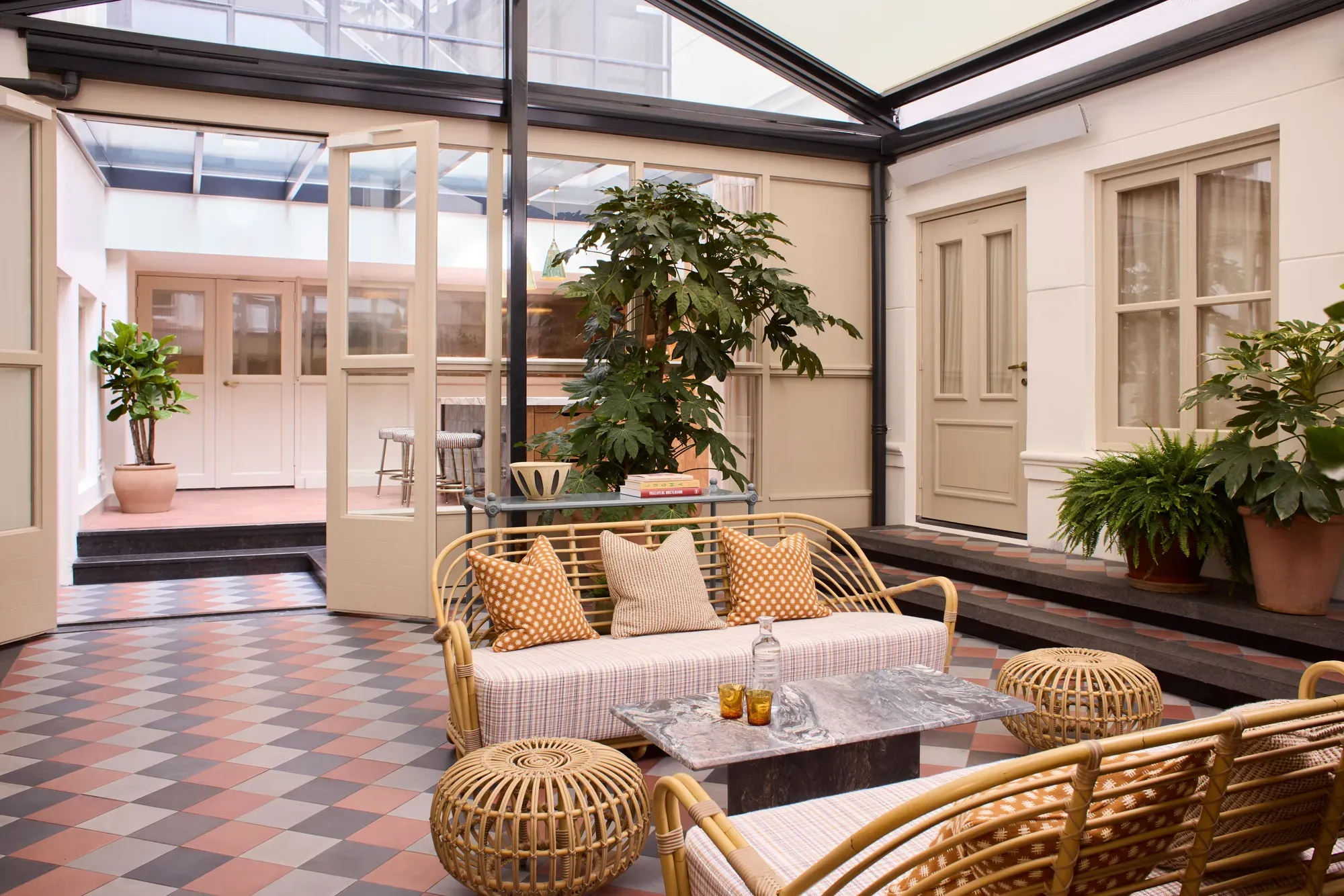 The courtyard of The Apartment at The Hoxton, Amsterdam with bamboo furniture and terracotta tiles