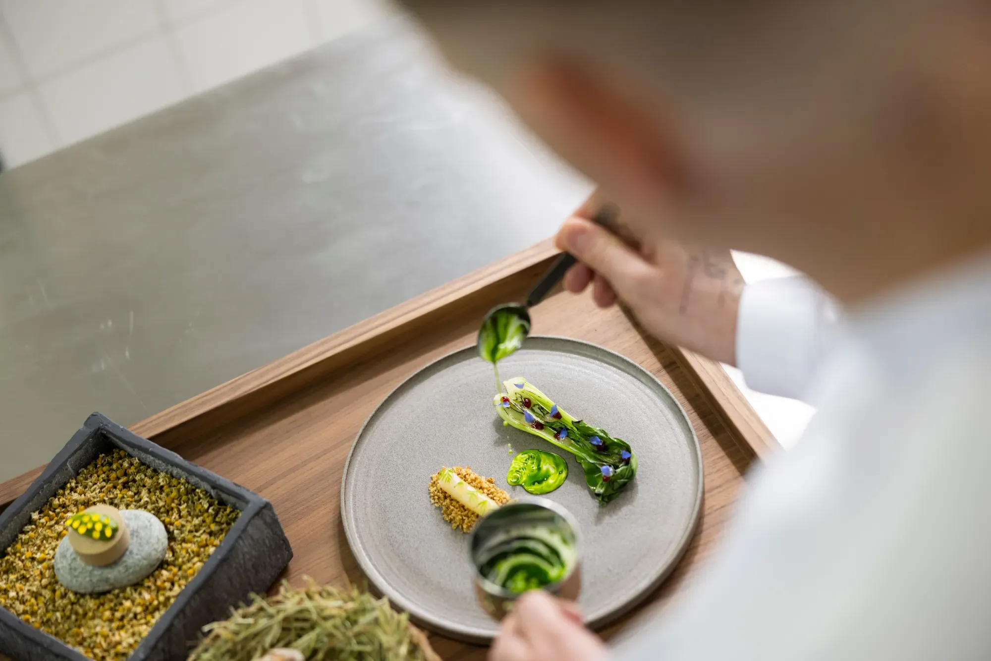 Clemens Gesser plating a course on a wooden tray at the Chef's Table