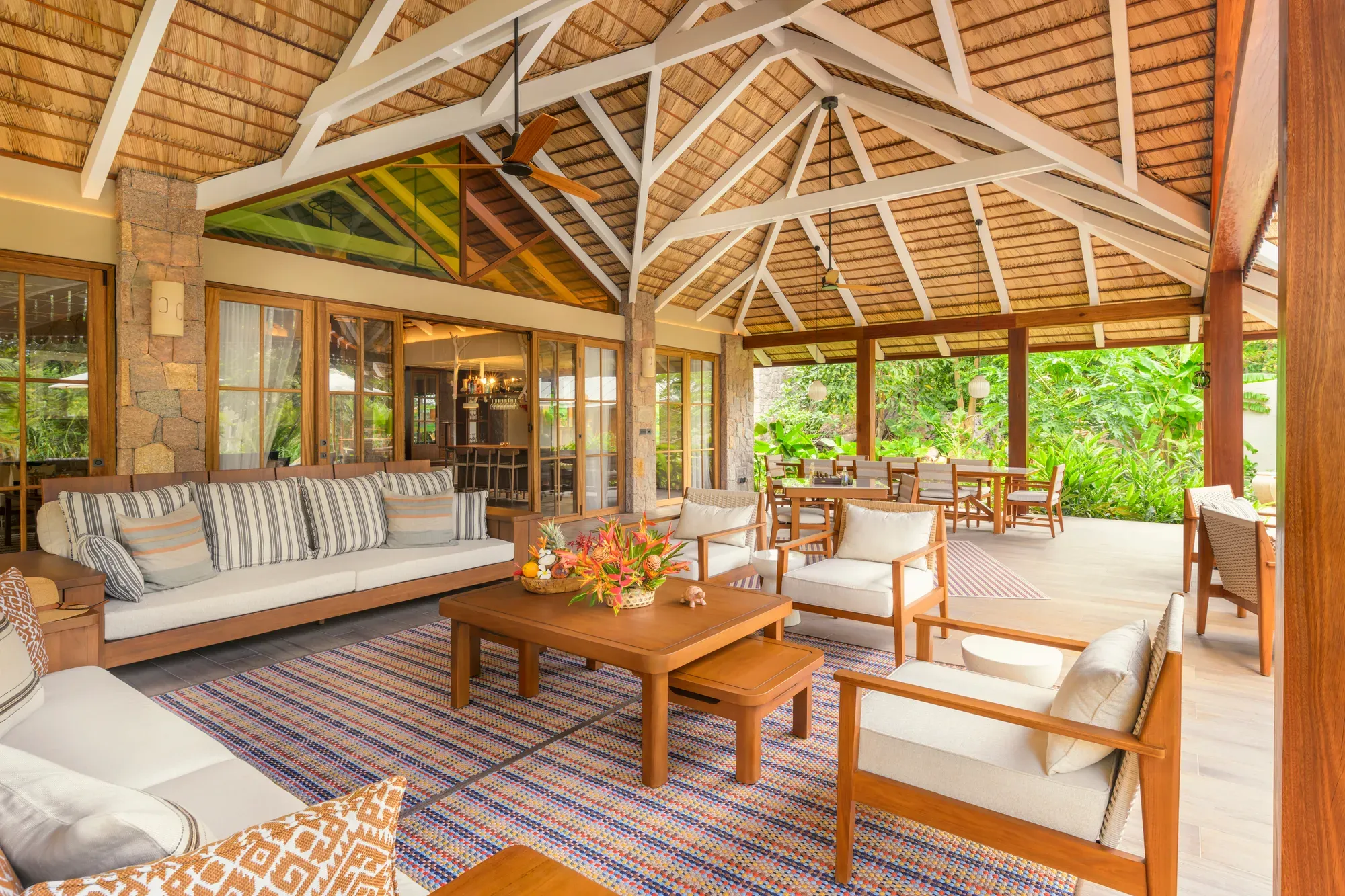 The covered veranda lounge of a villa at La Réserve Seychelles under a palm-leaf roof