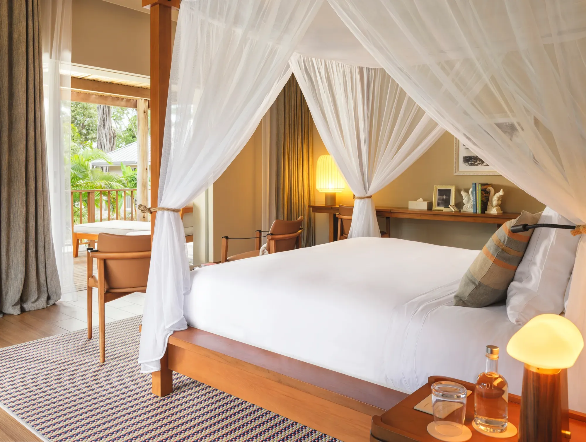 A bedroom with a four-poster bed and white curtains in a villa at La Réserve Seychelles