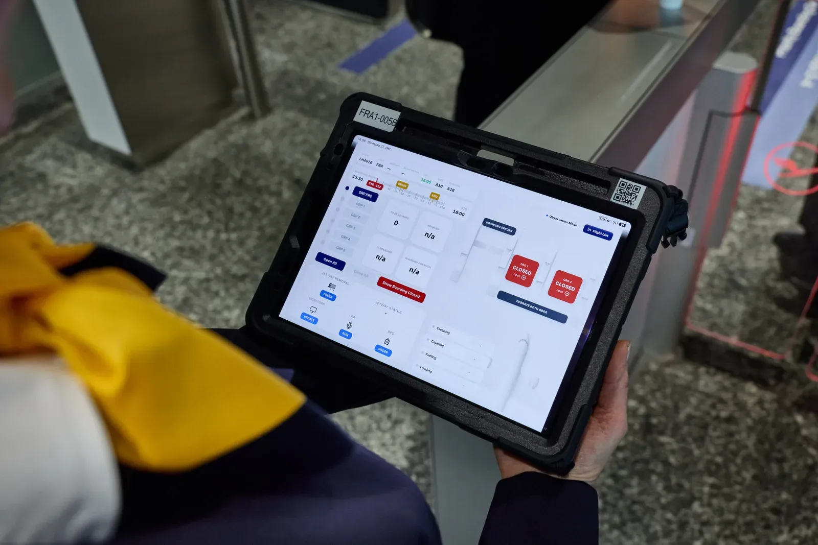 A Lufthansa staff member holding a tablet with the boarding system at Gate A16