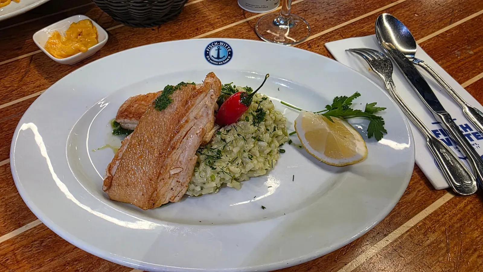 Halibut fillet on herb risotto with dill, a small red pepper and lemon at Fisch Witte, Munich