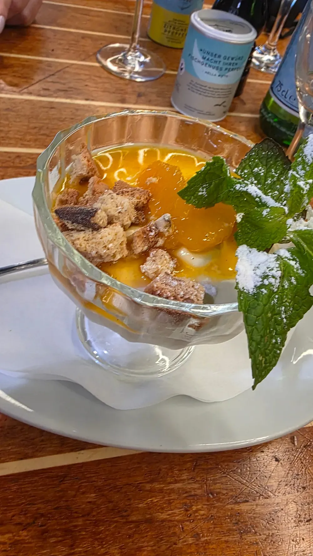 White chocolate mousse with orange segments, biscuit crumbs and mint leaves in a glass bowl at Fisch Witte