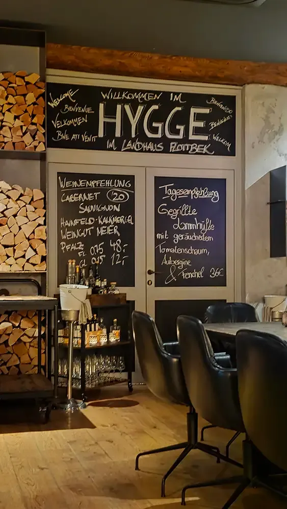 HYGGE chalkboard and stacked firewood at the entrance