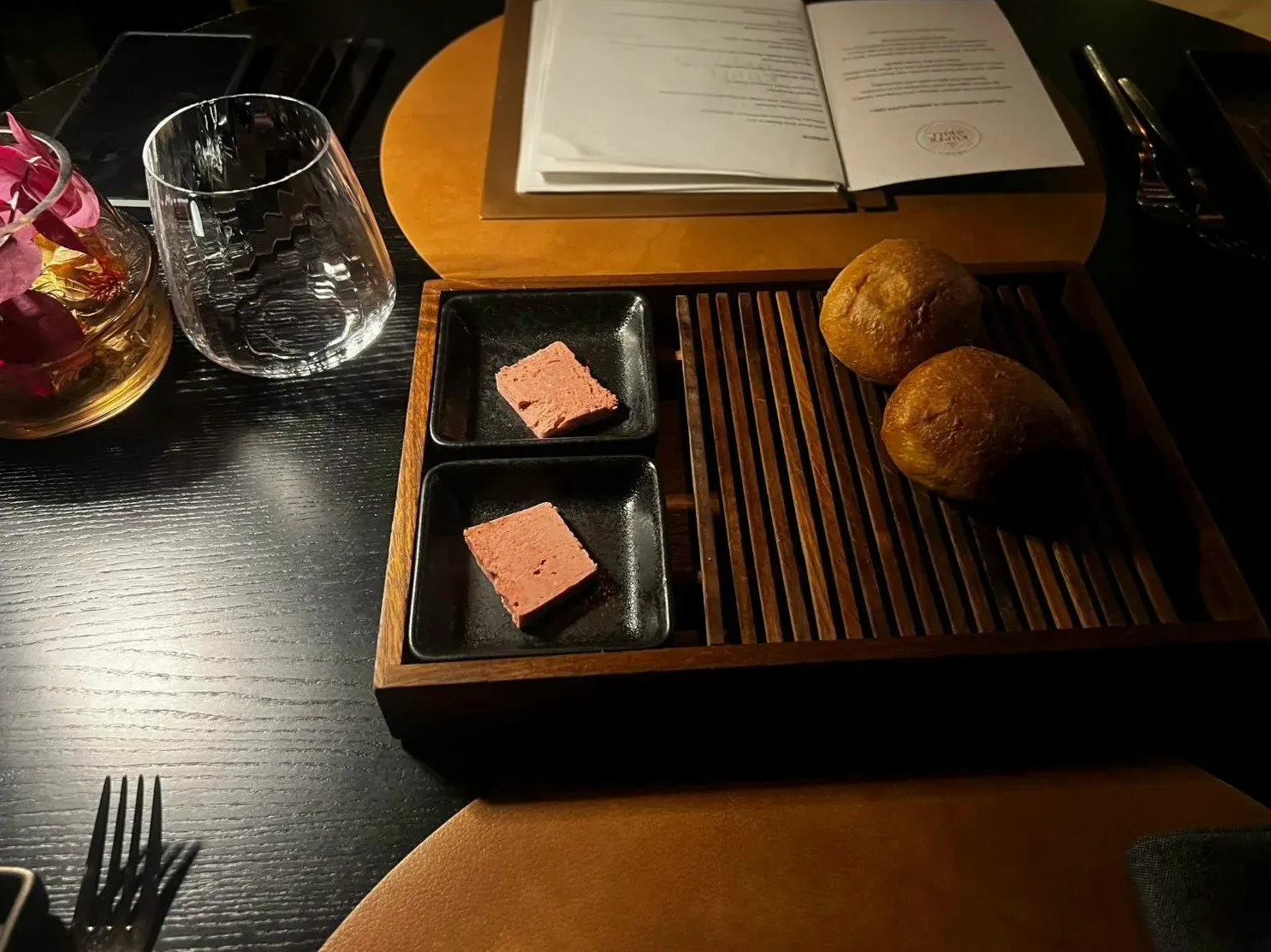 The greeting from the kitchen at the Kupfrgrill in Schruns: two bread rolls with garlic butter and sour cherry butter in a wooden box