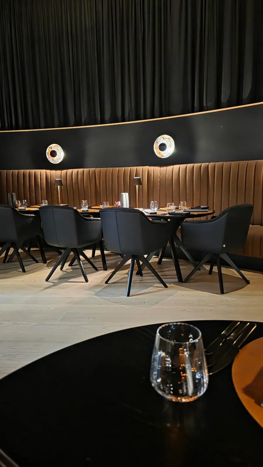 The curved banquette and black chairs in the dining room of the Kupfrgrill at AMRAI Suites, Schruns