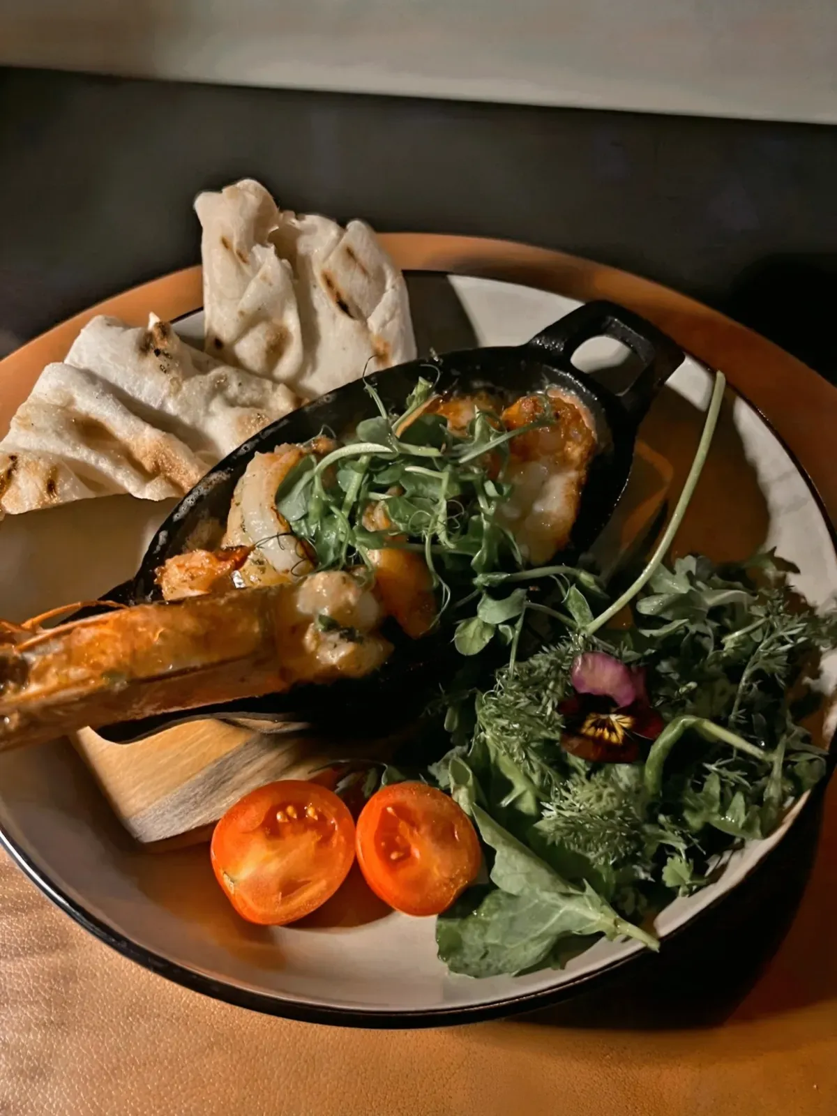 Grilled prawns in garlic butter in a cast-iron pan with flatbread and herb salad at the Kupfrgrill in Schruns