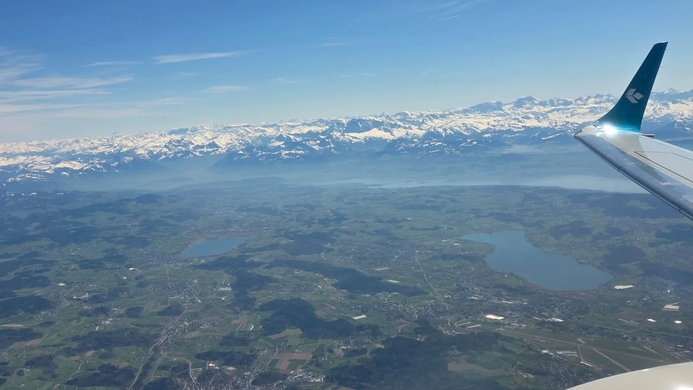 The Air Dolomiti winglet above Greifensee and Pfäffikersee, with Lake Zurich and the snow-covered Swiss Alps on the horizon