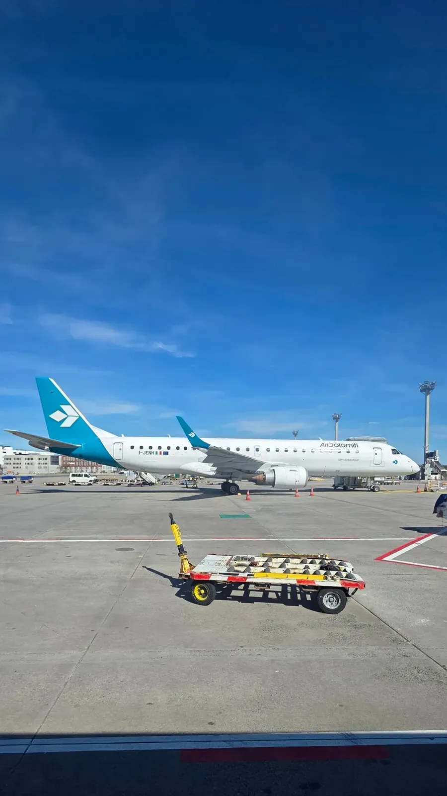 An Air Dolomiti Embraer in white and teal livery on the apron at Frankfurt Airport
