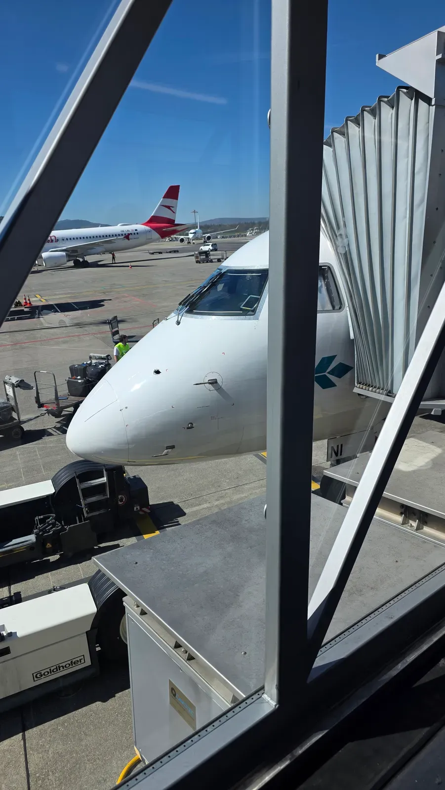 The Air Dolomiti Embraer E190 at the jet bridge in Terminal A of Zurich Airport, with an Austrian Airlines Airbus behind
