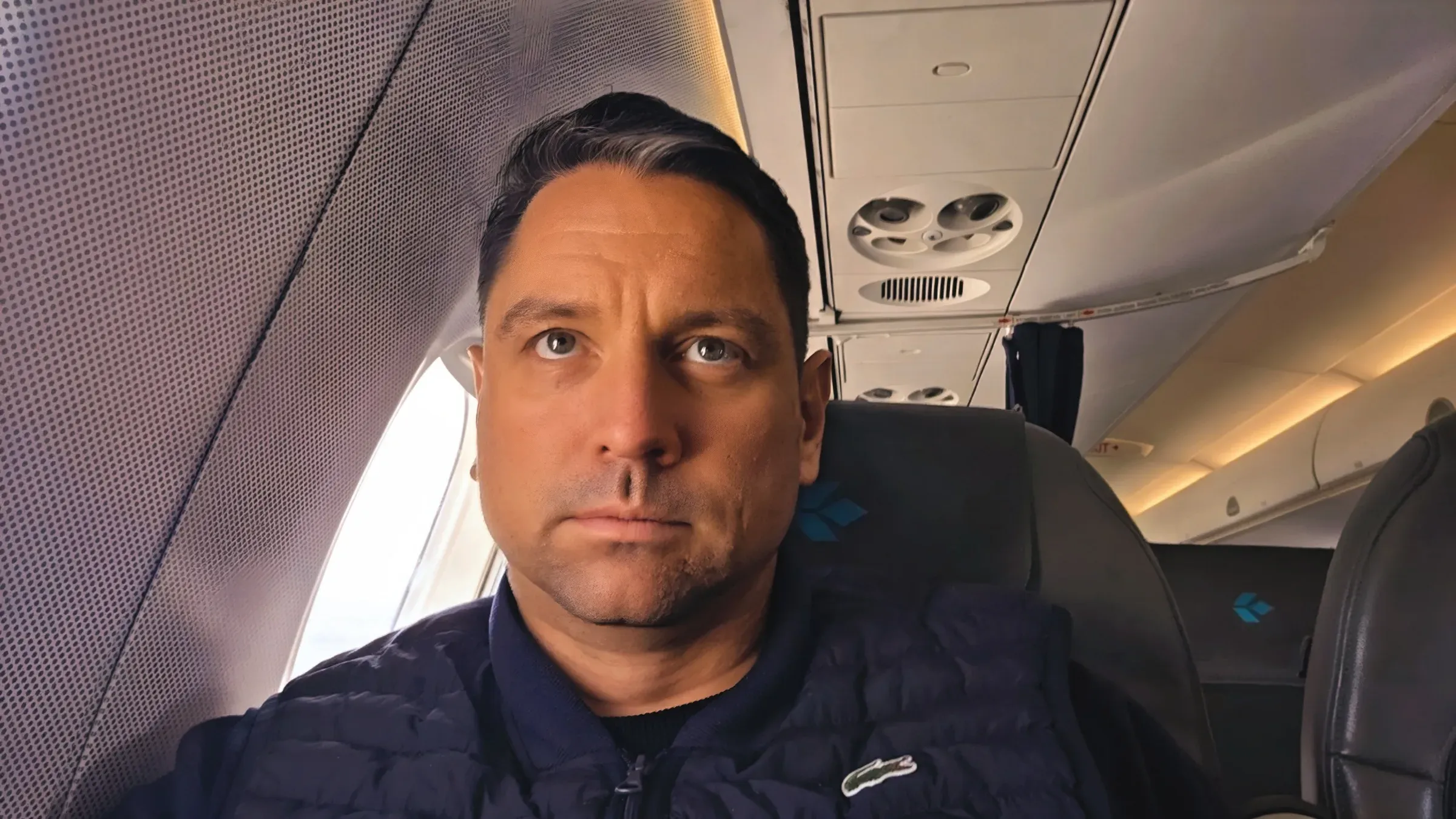 Roger Hohl in his window seat in Air Dolomiti Business Class on the Embraer E190 from Zurich to Frankfurt, with the Air Dolomiti logo on the headrest