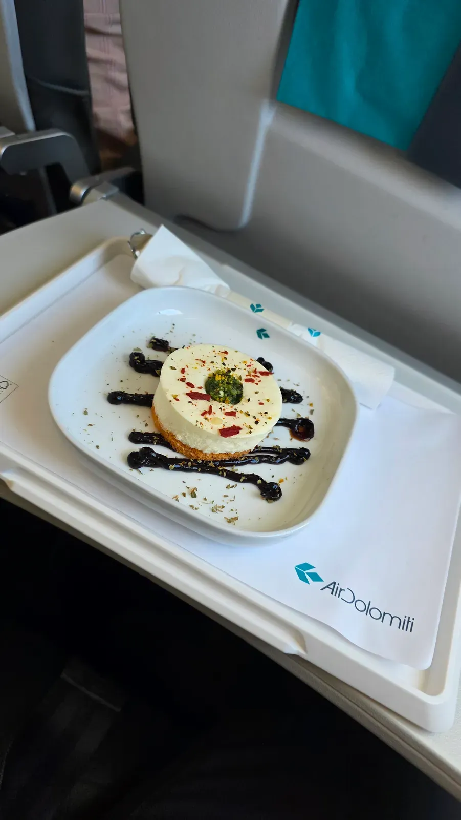 A savoury cheesecake with pesto, dried tomato and pistachio on a plate in Air Dolomiti Business Class