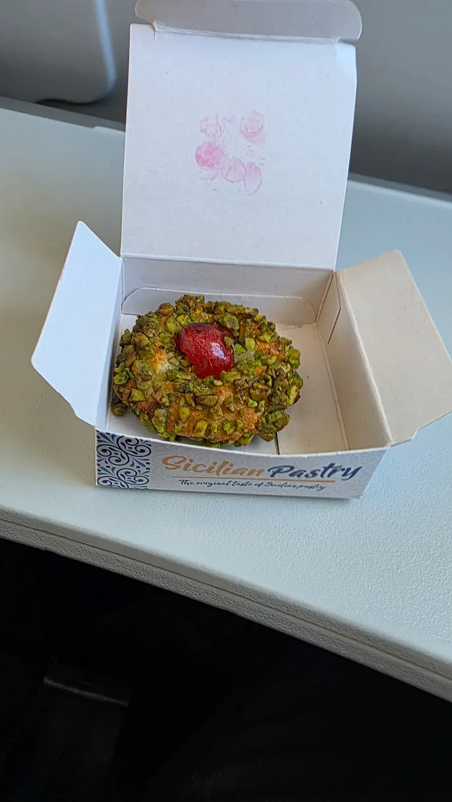 The Sicilian Pastry with chopped pistachios and a candied cherry in its open box