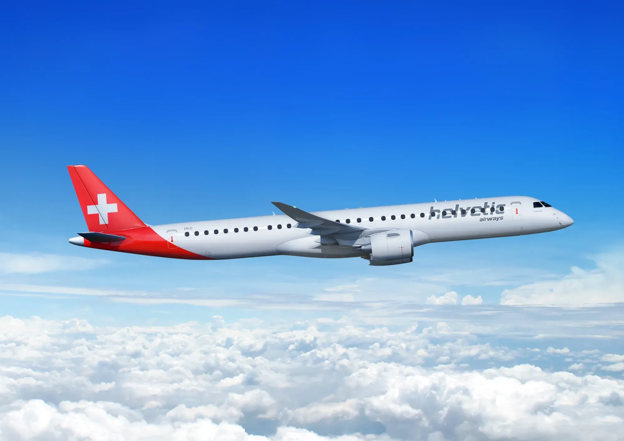 The Helvetic Airways Embraer E195-E2 in flight above the clouds, in the airline's red and white livery