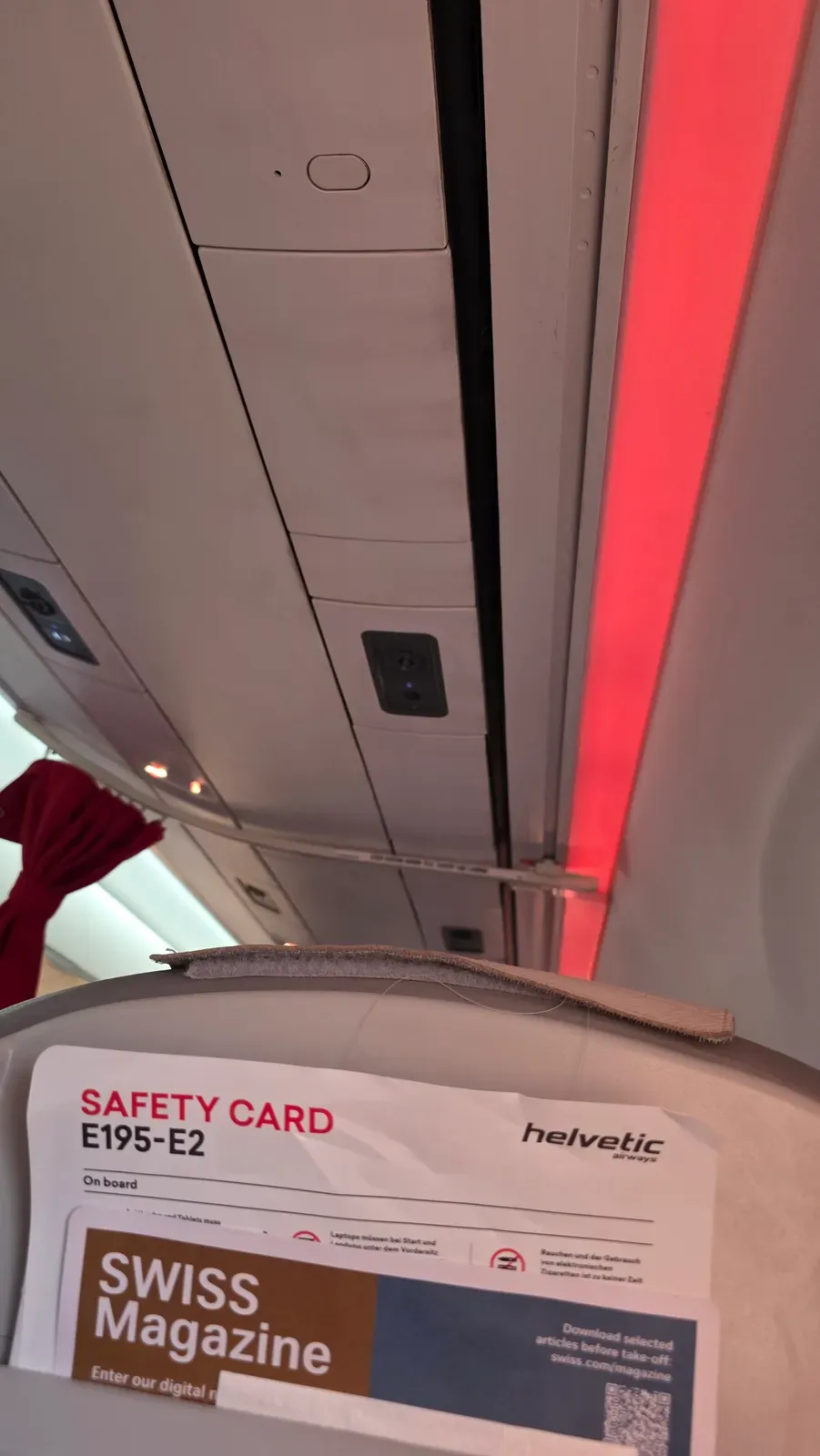 Overhead panel and ambient lighting on the Helvetic Embraer E195-E2, with the E195-E2 safety card