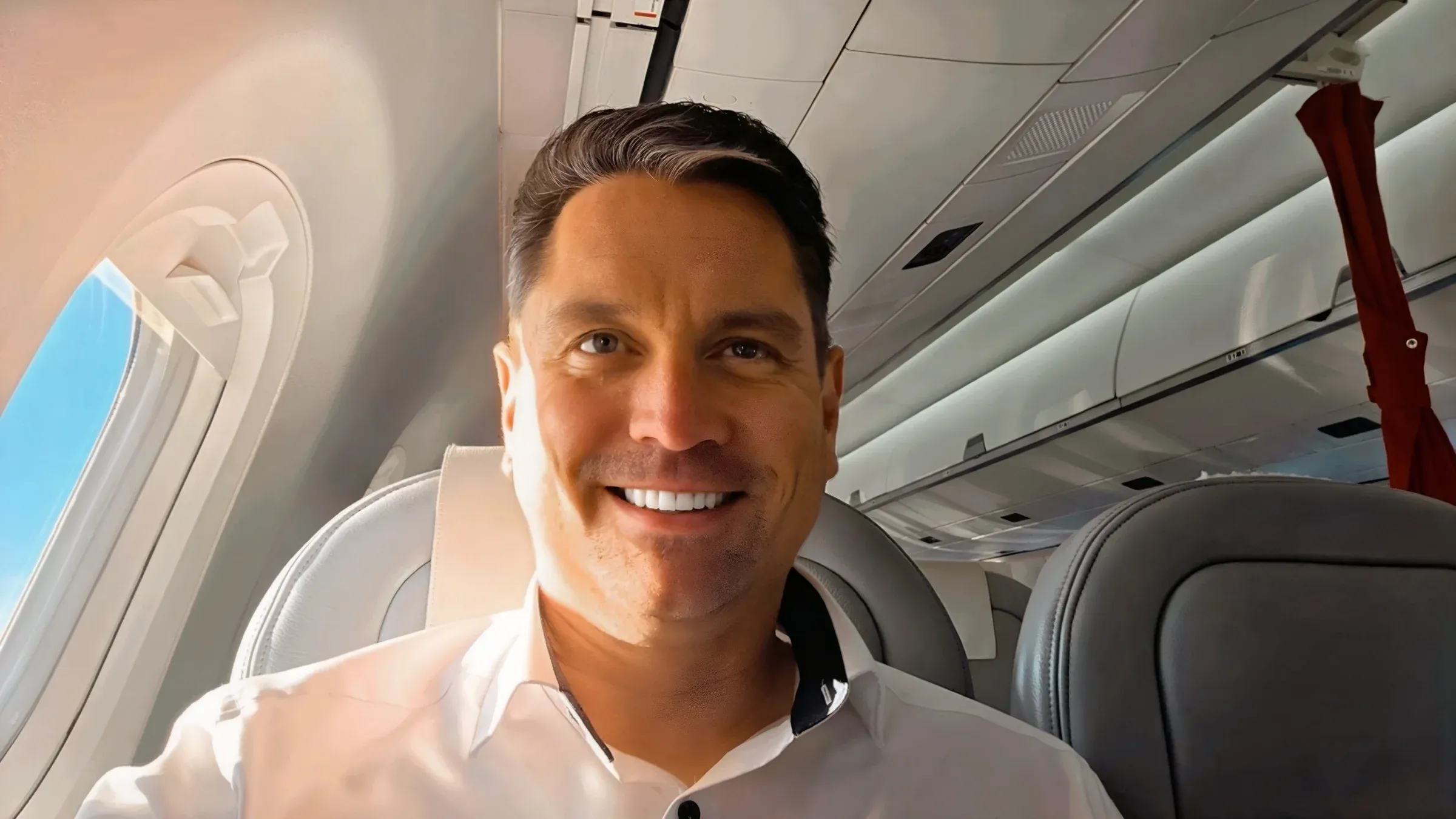 Roger Hohl smiling at his window seat in Business Class on the Helvetic Embraer E195-E2 flying for SWISS from Hamburg to Zurich