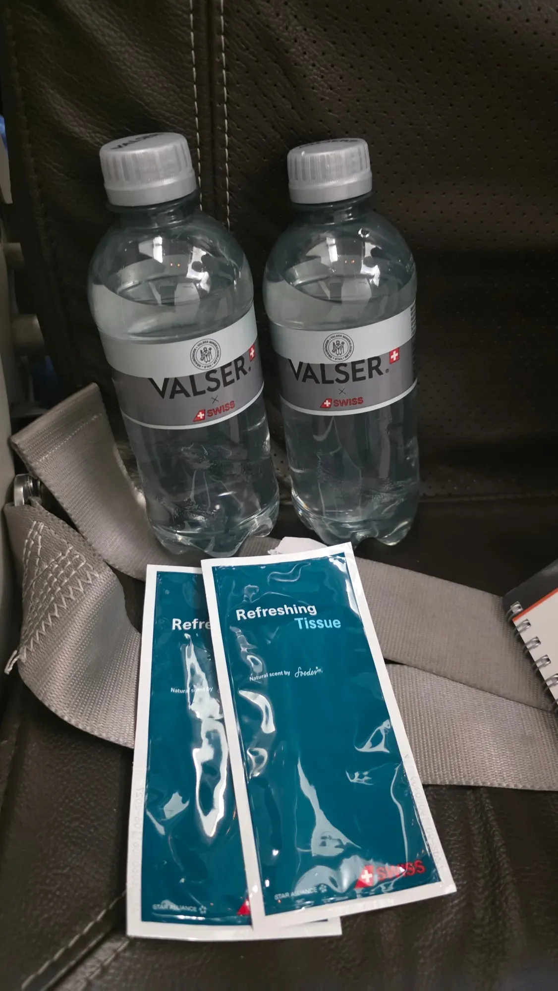 Two bottles of Valser x SWISS water and two SWISS refreshing tissues on the seat