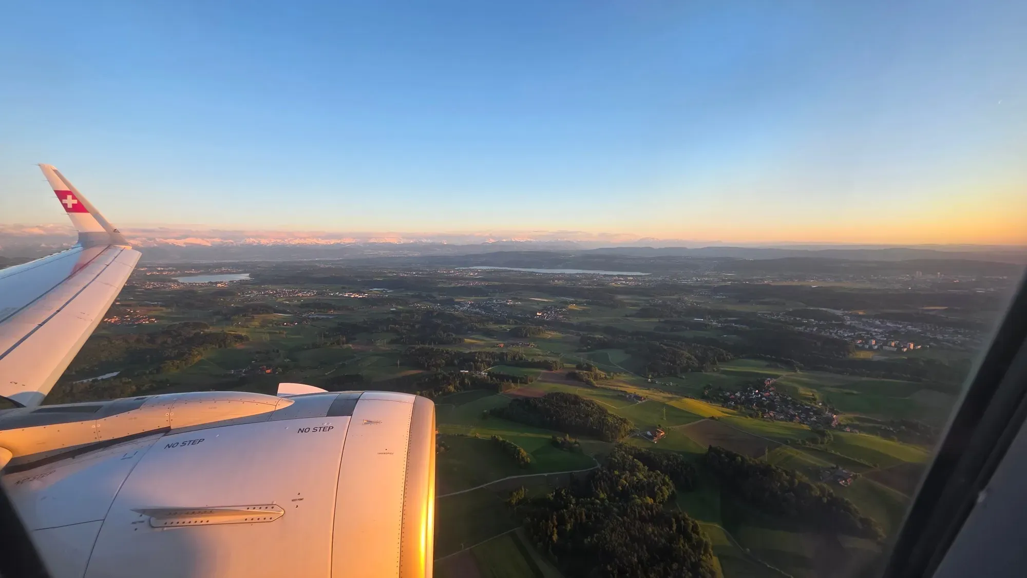 Approach to Zurich over green hills and lakes with the Alps on the horizon