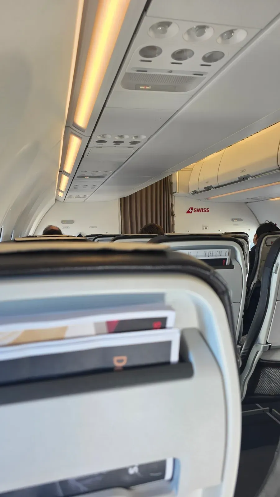 SWISS A321neo cabin with warm ceiling lighting and the curtain behind Business Class