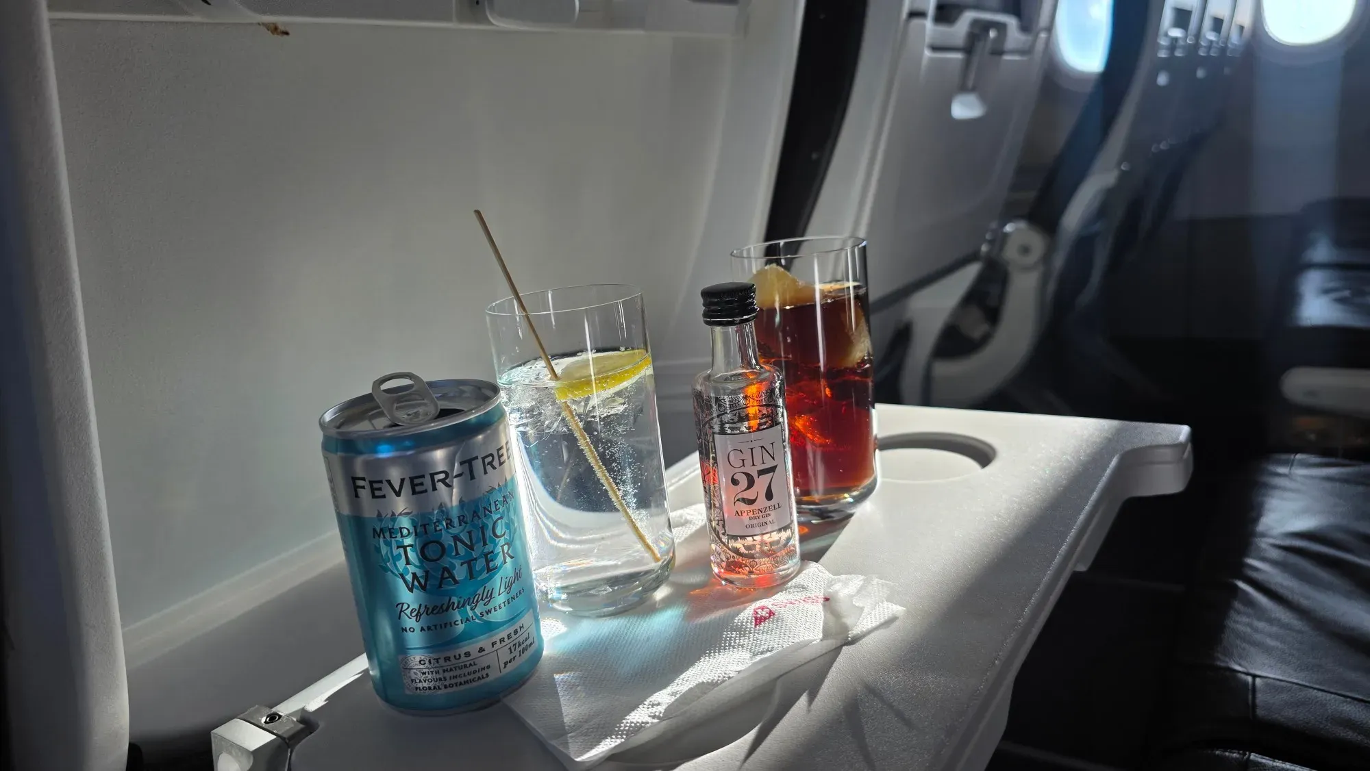 Gin 27 from Appenzell, Fever-Tree Mediterranean Tonic and a soft drink on the tray table in SWISS A321neo Business Class
