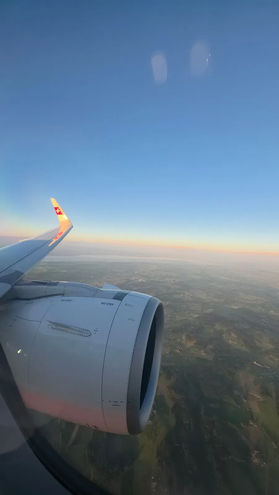 Wing of the SWISS A321neo over Eastern Switzerland with a lake on the horizon in the low sun