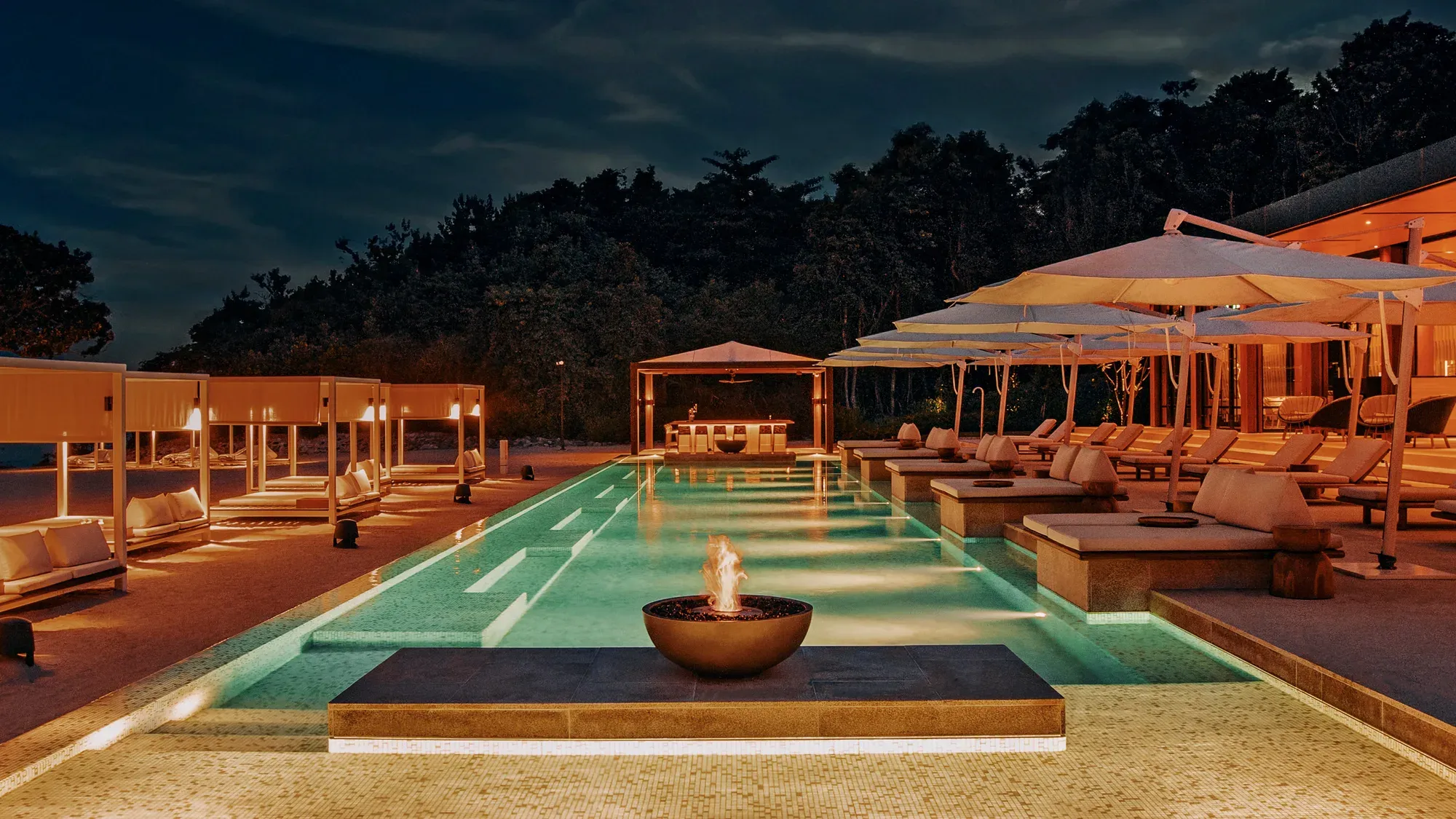 The Ember Beach Club at Mandarin Oriental, Desaru Coast at dusk, with a fire bowl in the pool
