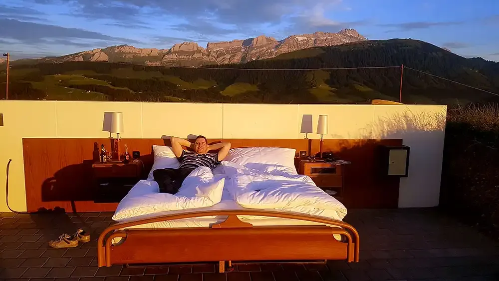 Guest in the open-air bed at sunset with the Alpstein behind