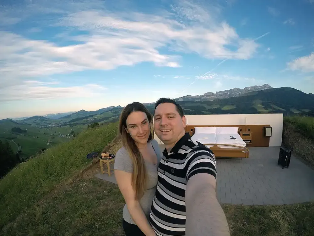 Roger Hohl taking a selfie with the open-air bed and the mountains behind