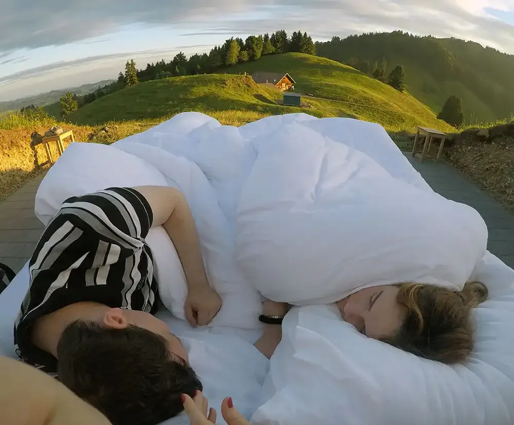 Guests under the duvet at sunrise in the open-air bed