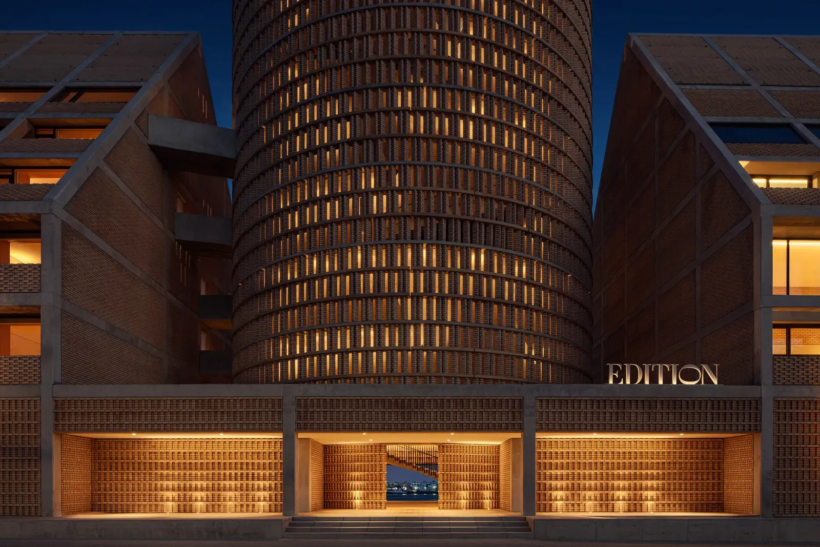 The brick façade and cylindrical drum of The Cape Town EDITION at dusk